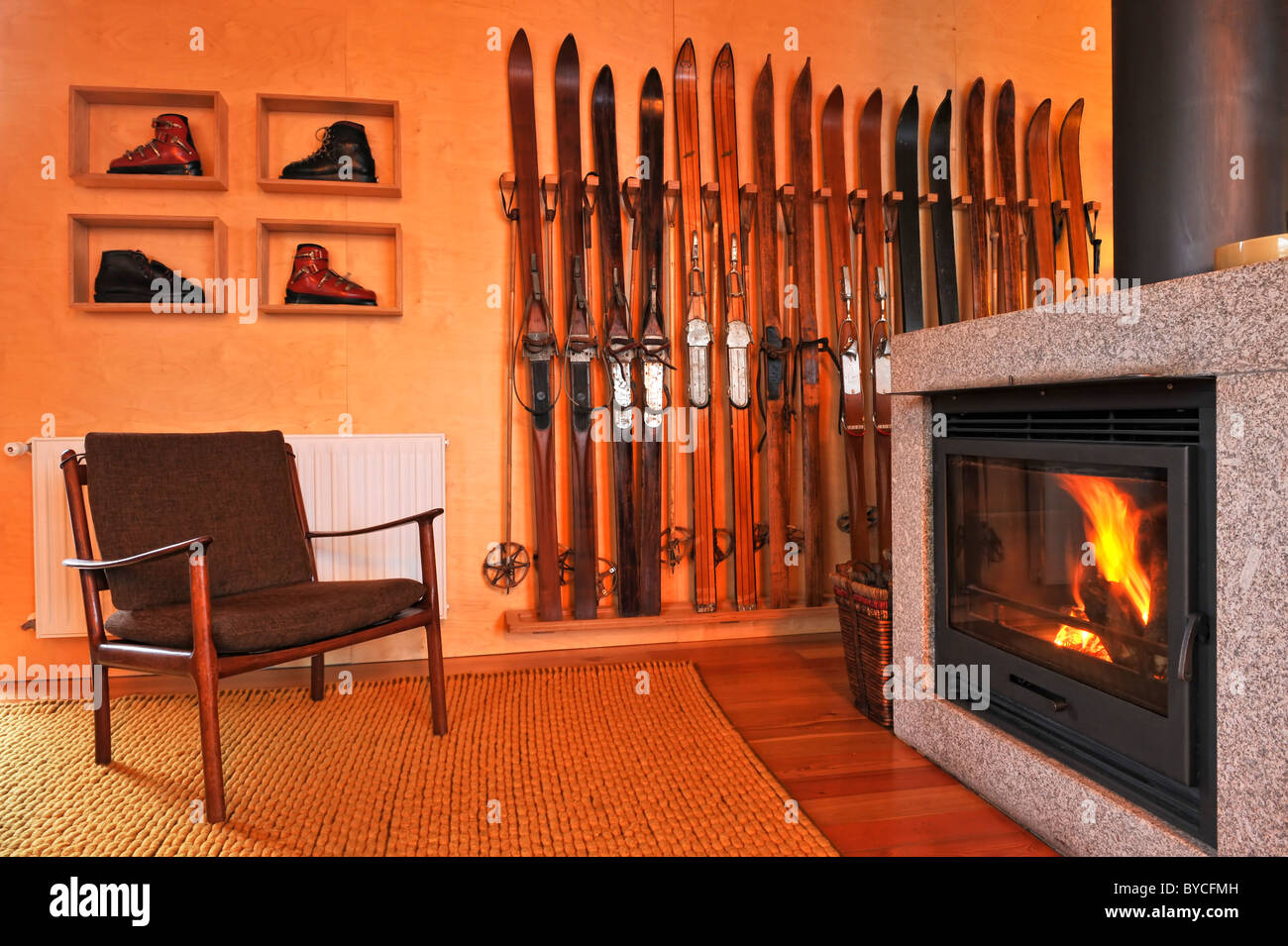 Chalet living room with inviting fireplace vintage ski rack and ski boots and scandinavian furniture Stock Photo