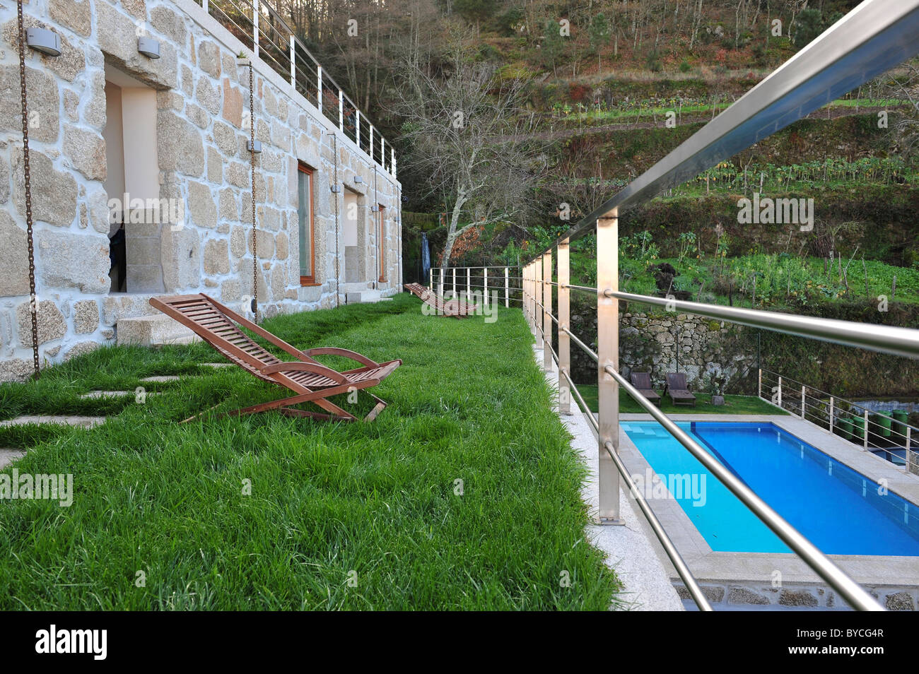 Terrace with wooden lounge chair on lawn over a swimming pool at the Casas da Lapa hotel, Lapa dos Dinheiros, Portugal Stock Photo