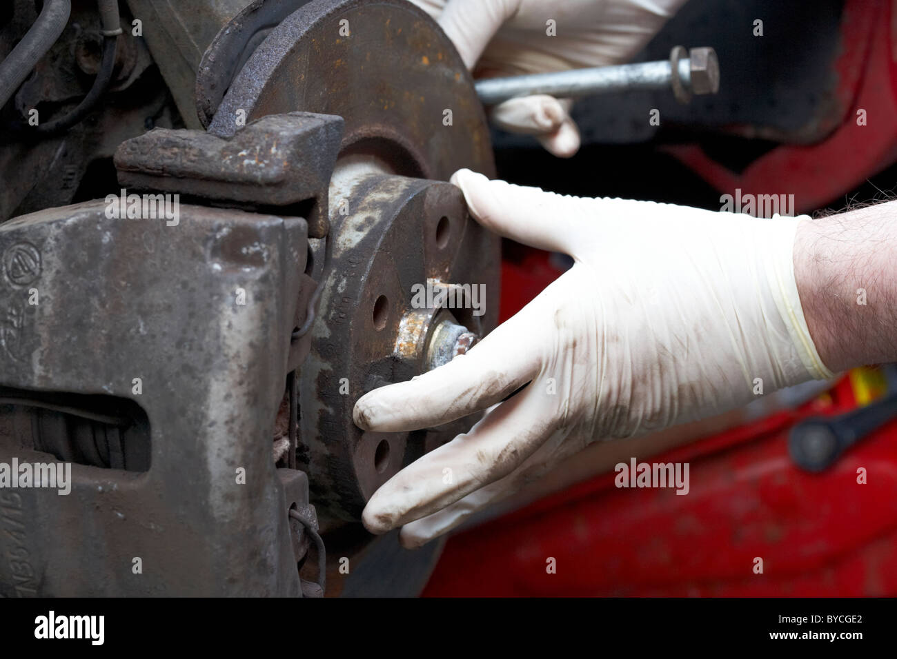 mechanic wearing rubber gloves performing car maintenance on a rusty