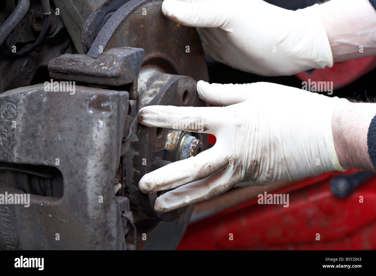 mechanic wearing rubber gloves performing car maintenance on a rusty