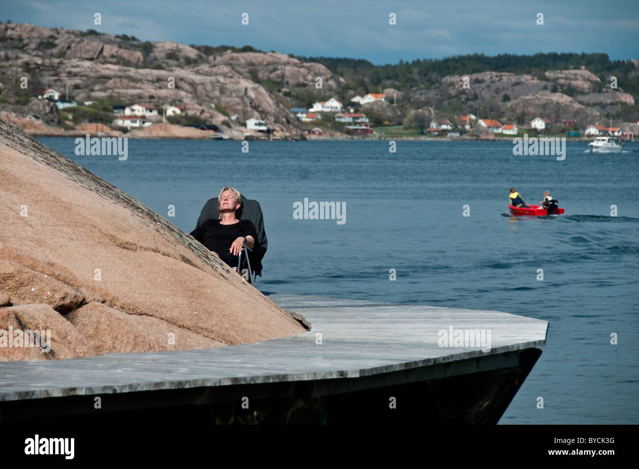 A woman taking in the early summer sunshine in June in Bovallstrand in Bohuslän on the west coast of Sweden Stock Photo