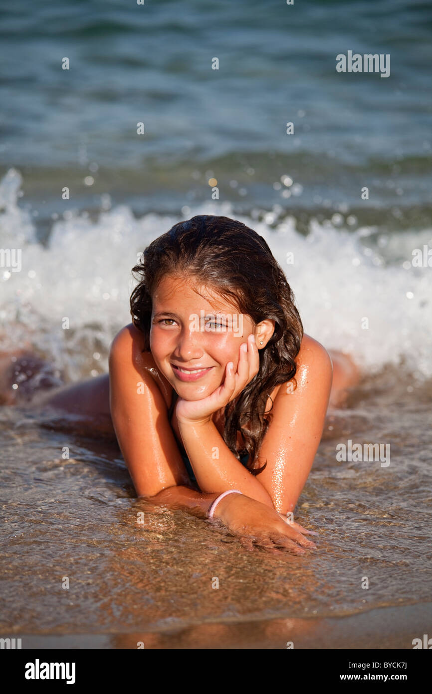 Happy young girl laying by the waterline smiling Stock Photo