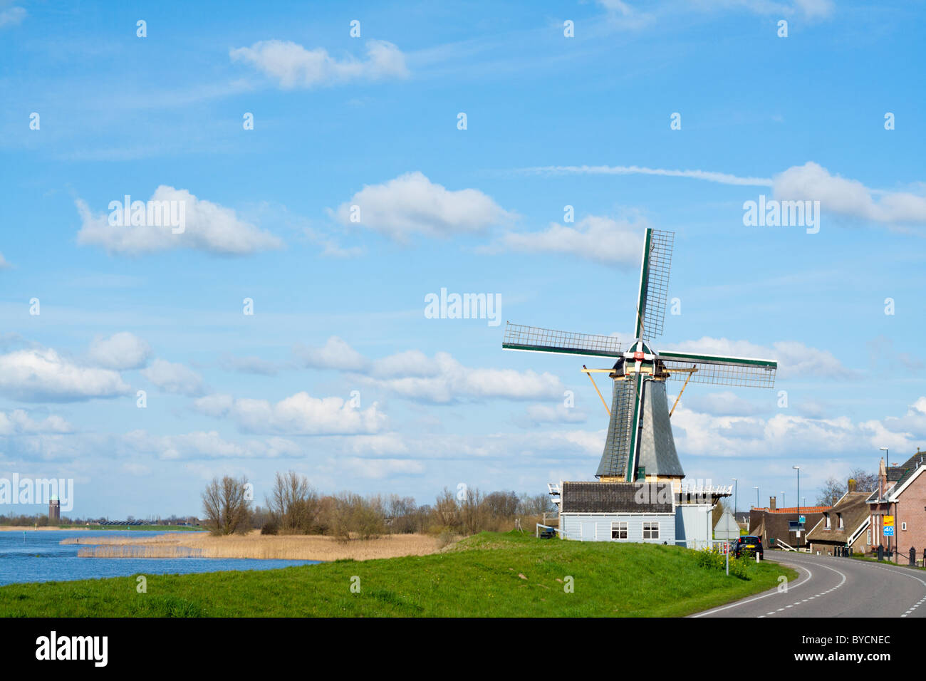 Small Dutch town next to a dyke with canal and windmill Stock Photo