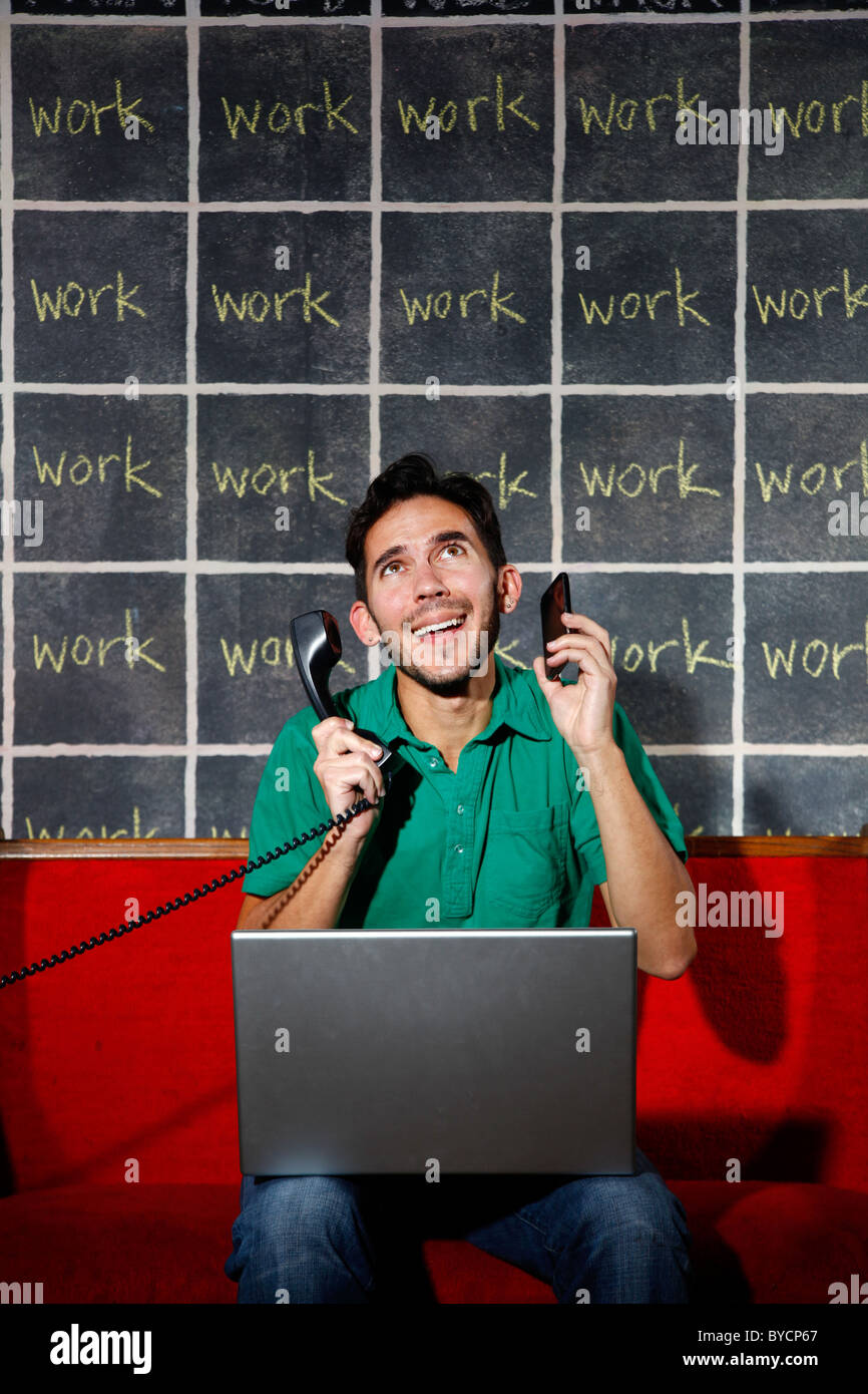 Frustrated office worker overworked workaholic talking on phone and working on laptop. Stock Photo