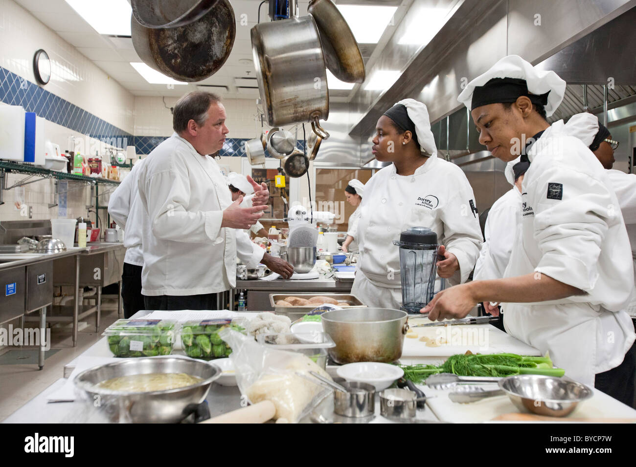 Instructor John Adamski works with students preparing food at the Dorsey Culinary Academy, a private career training school. Stock Photo