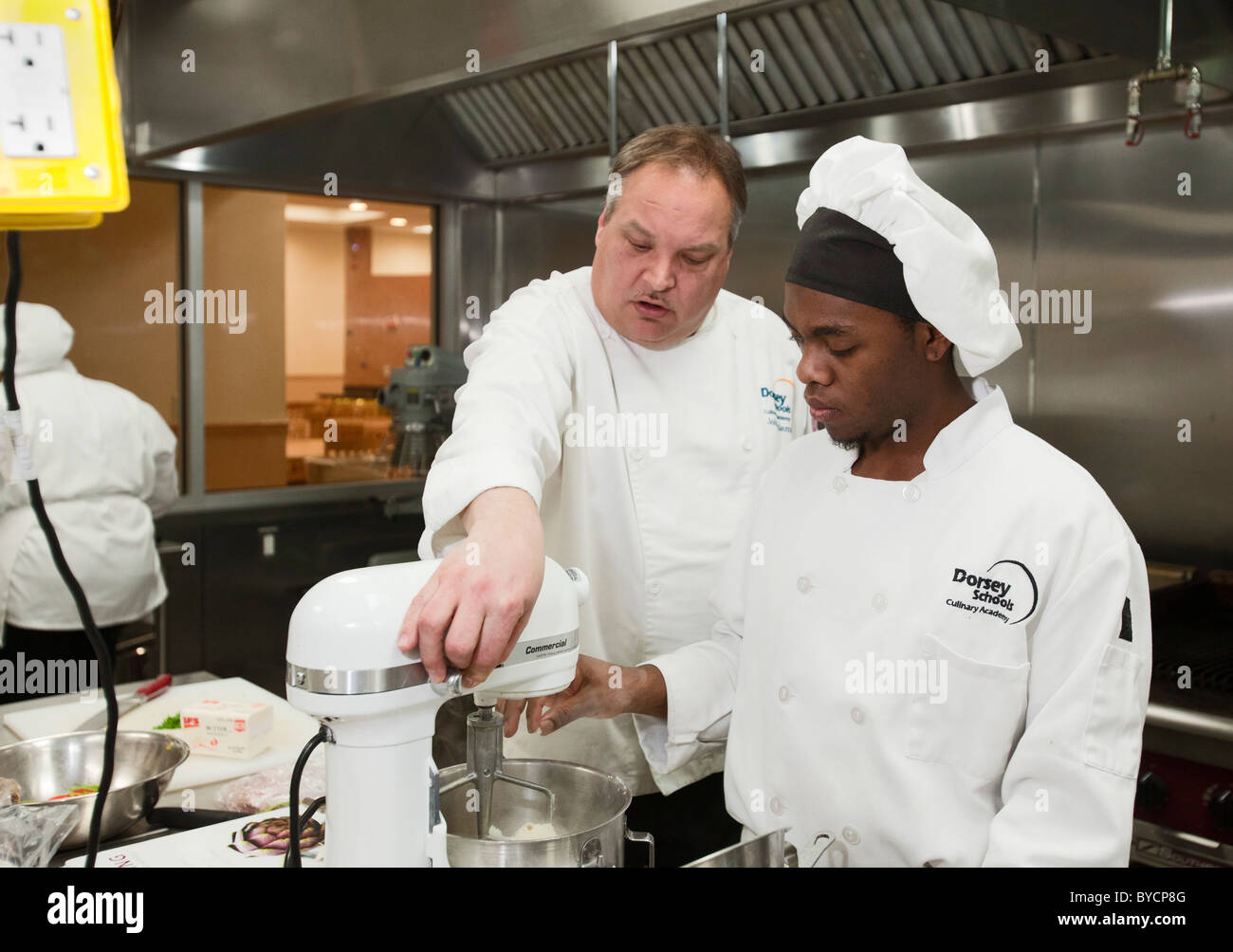 Instructor John Adamski works with a student preparing food at the Dorsey Culinary Academy, a private career training school. Stock Photo