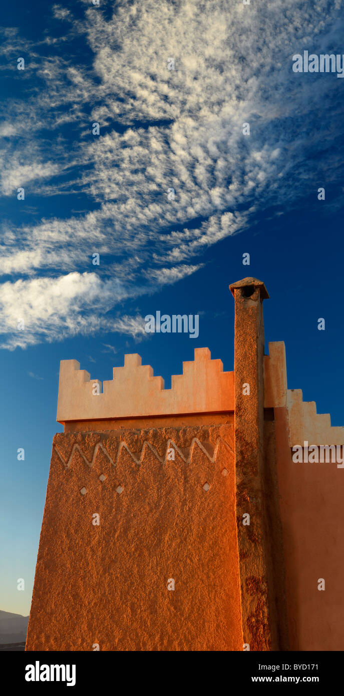 Texture and pattern of Berber pise architecture with chimney and puffy clouds at sunrise in Tinerhir Morocco Stock Photo