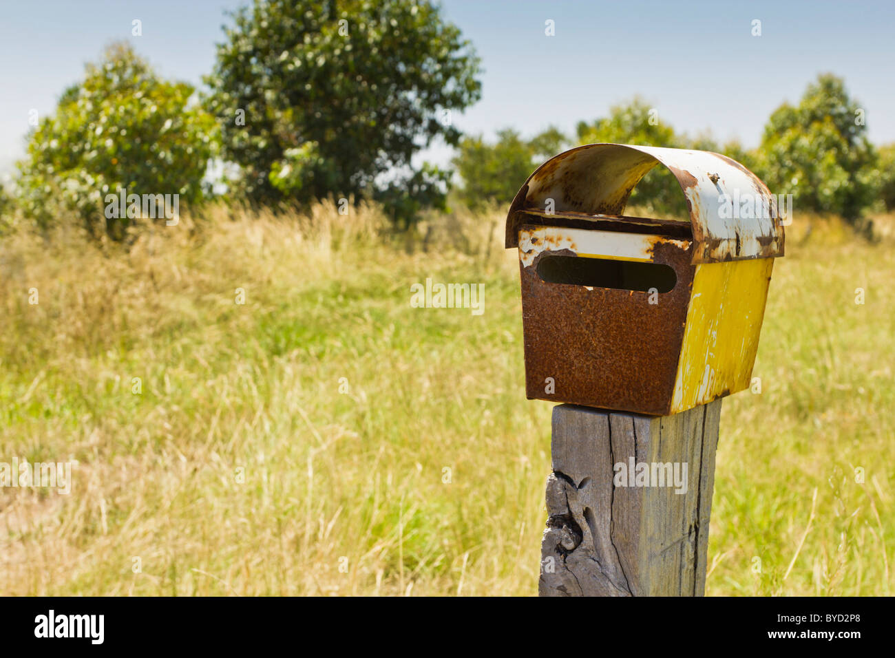 Rusty rural letterbox on wooden post. Stock Photo