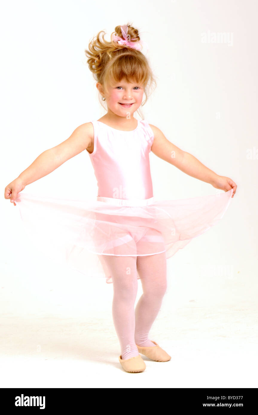 Little smiley girl wearing a pink ballet outfit is dancing holding her