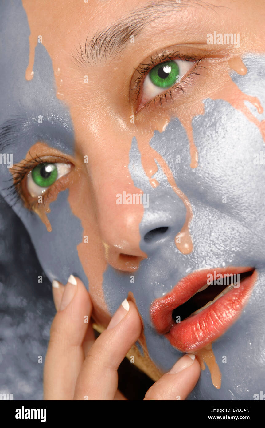 Silver paint washing out of woman face revealing clean skin Stock Photo