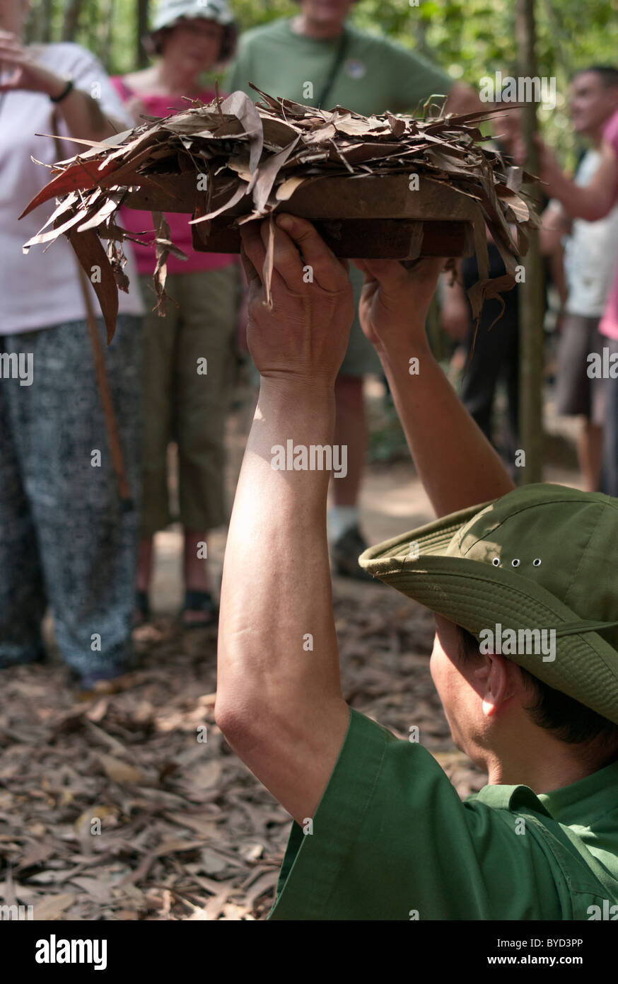 Cu Chi Tunnels Vietnam, used during the War. Guide demonstrates access to tunnels before tourists. Stock Photo