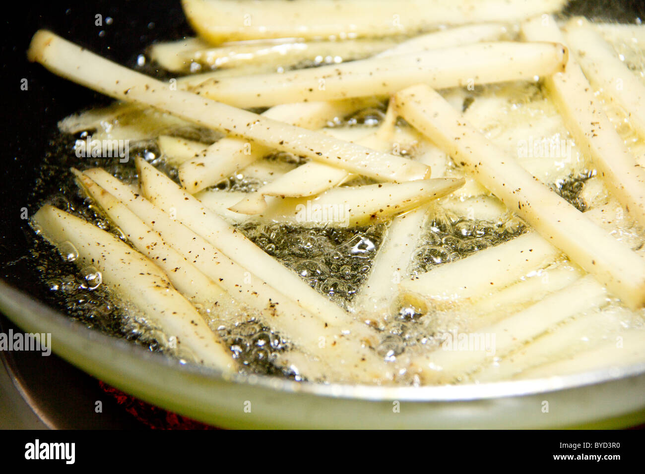 Frying french fries in a pan with old over a hot stove Stock Photo