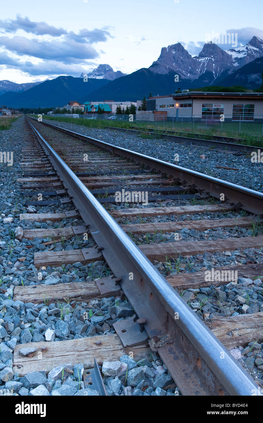 Train tracks running through Canmore, Alberta, Canada.  The Three Sisters peaks are in the distance. Stock Photo