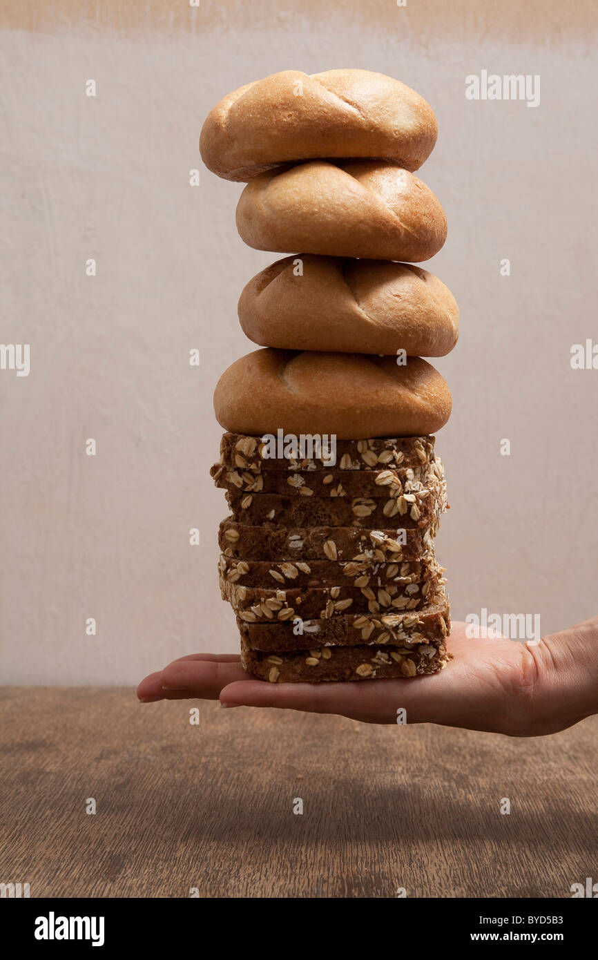 Hand holding a stack of bread rolls and sliced bread Stock Photo Alamy