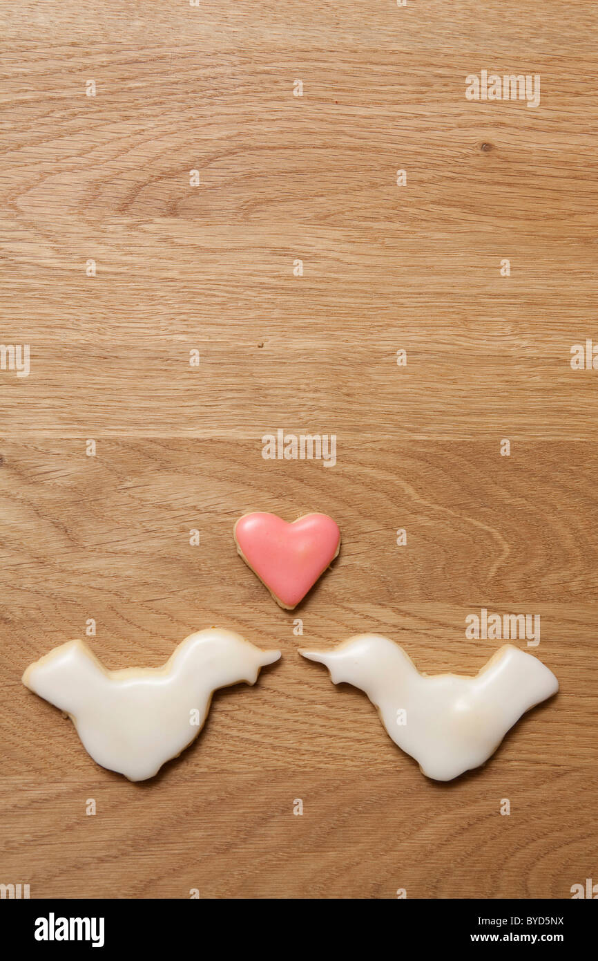 Two white birds and a heart biscuit, love Stock Photo