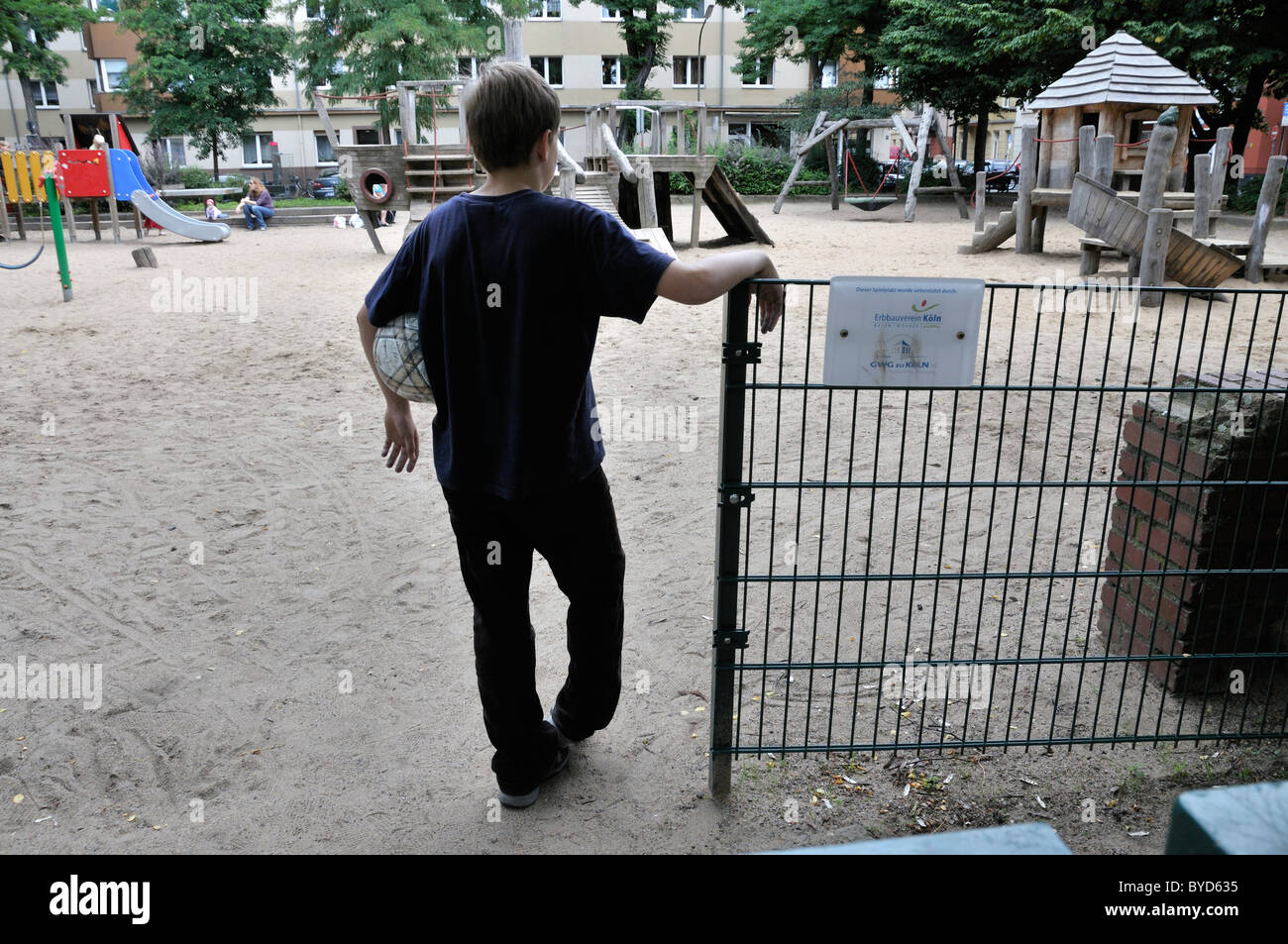 Lonely boy, 10 years, at the entrance to a playground, Cologne, North Rhine-Westphalia, Germany, Europe Stock Photo