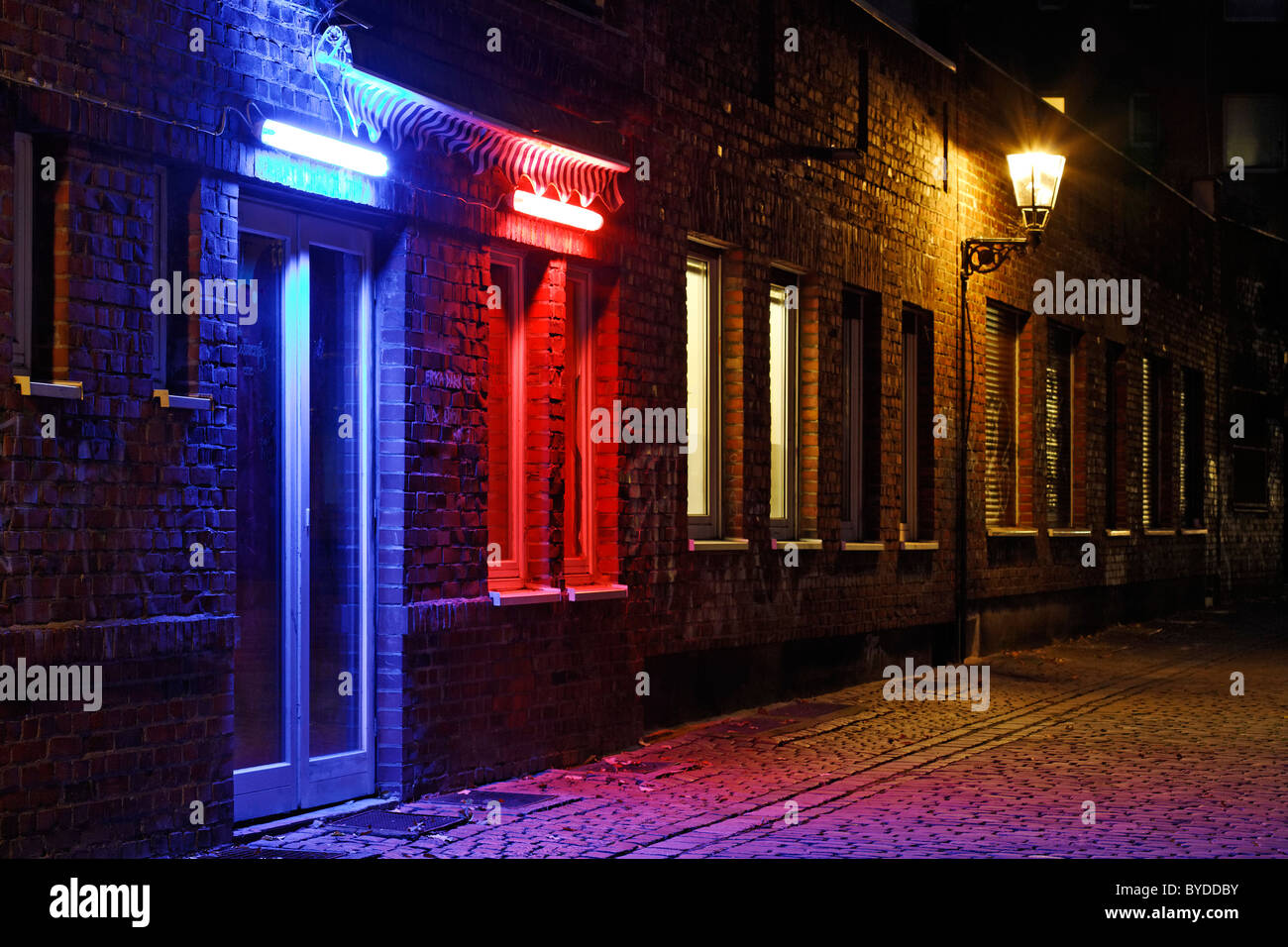 Alley in the historic district, nice ambiance, blue illuminated door, red illuminated window, Duesseldorf Stock Photo