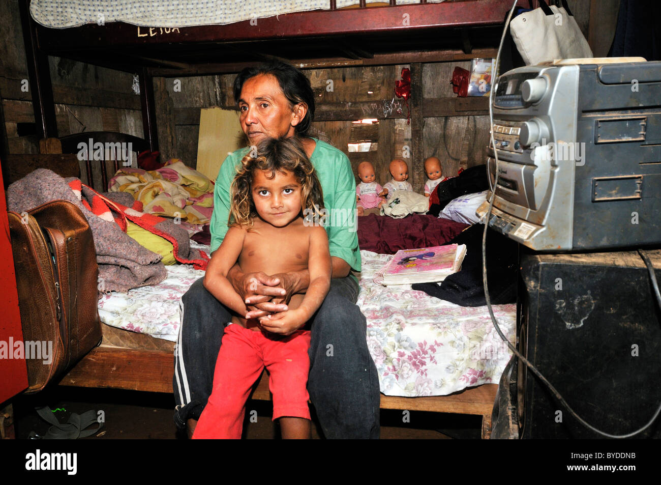 Mother, 43, and daughter, 8, sitting on a bed in their humble shack in a Favela or shanty town, the family lives by collecting, Stock Photo