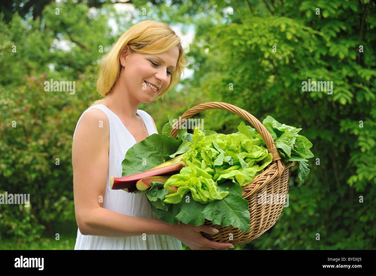 Young woman holding basket with vegetable Stock Photo - Alamy