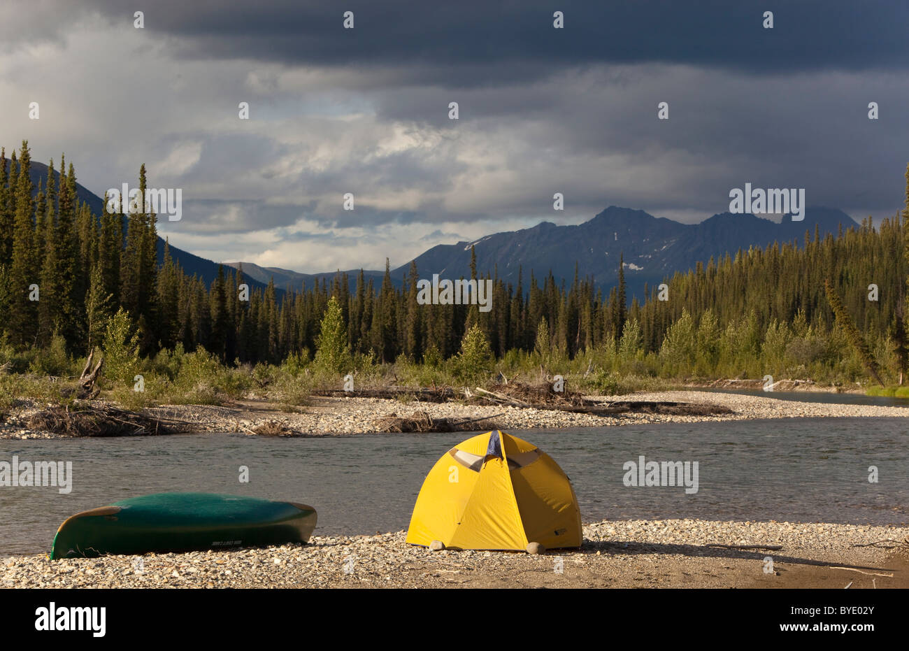 Camp on gravel bar, tent and canoe, Pelly Mountains behind, upper Liard