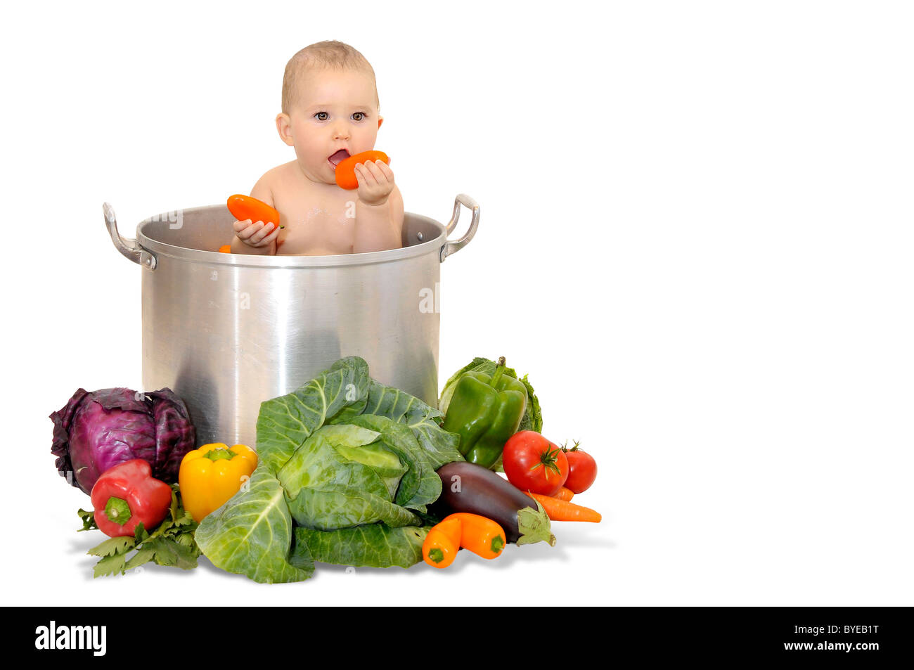 Beautiful young baby in a pan with vegetables Stock Photo
