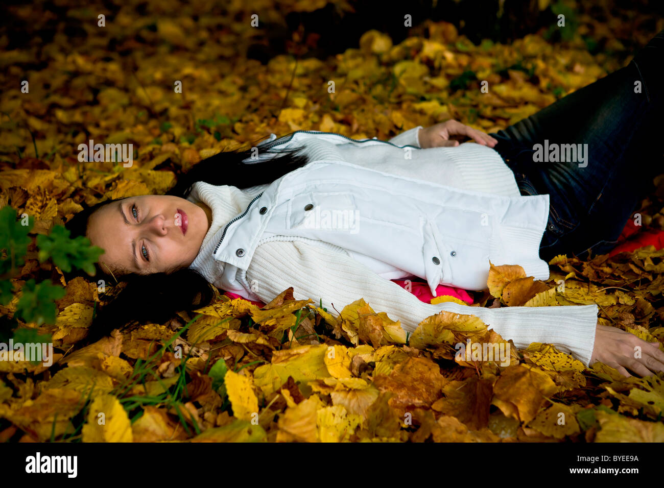 Young woman lying in autumn leaves Stock Photo - Alamy