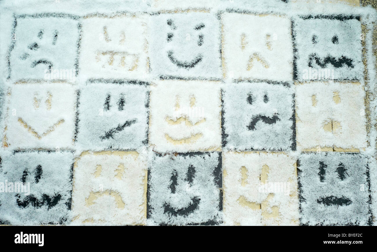 Different faces and moods drawn in snow on an outdoor chess board Stock Photo