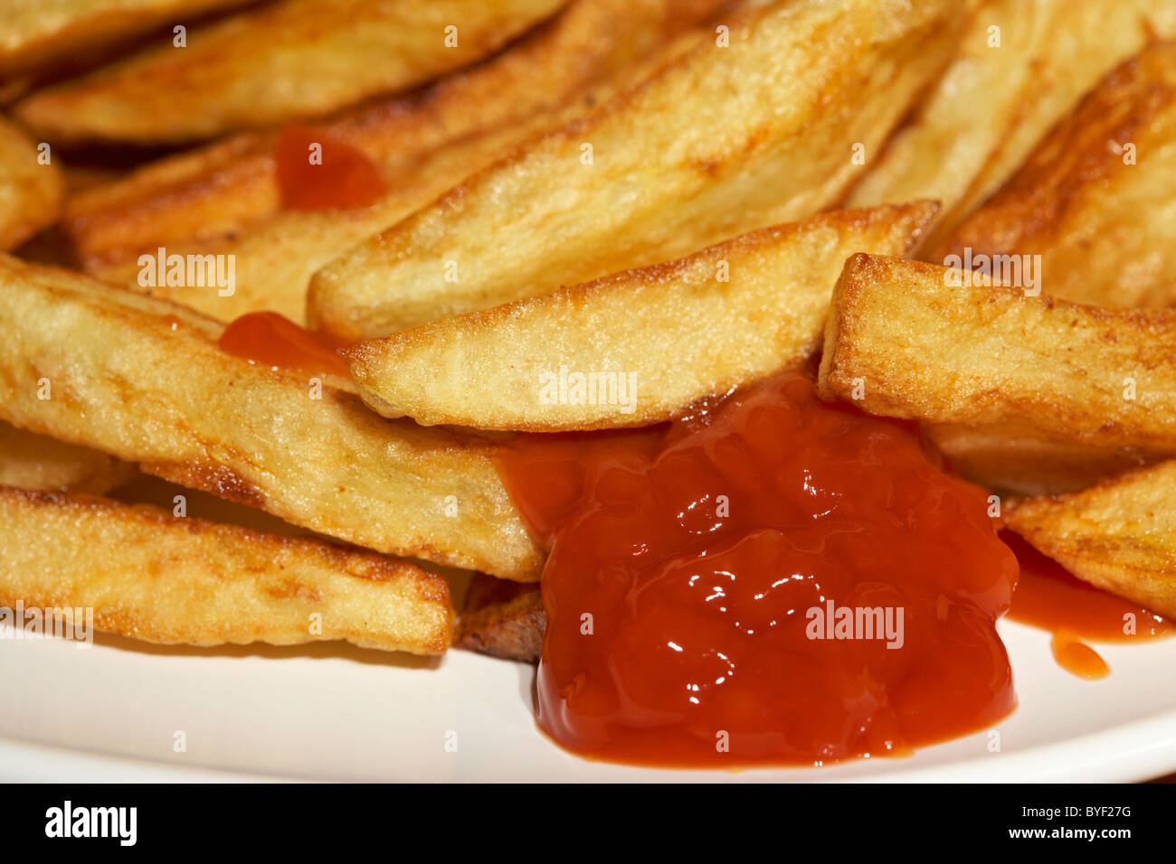 home made chips and tomato sauce ketchup on a plate in the uk Stock Photo