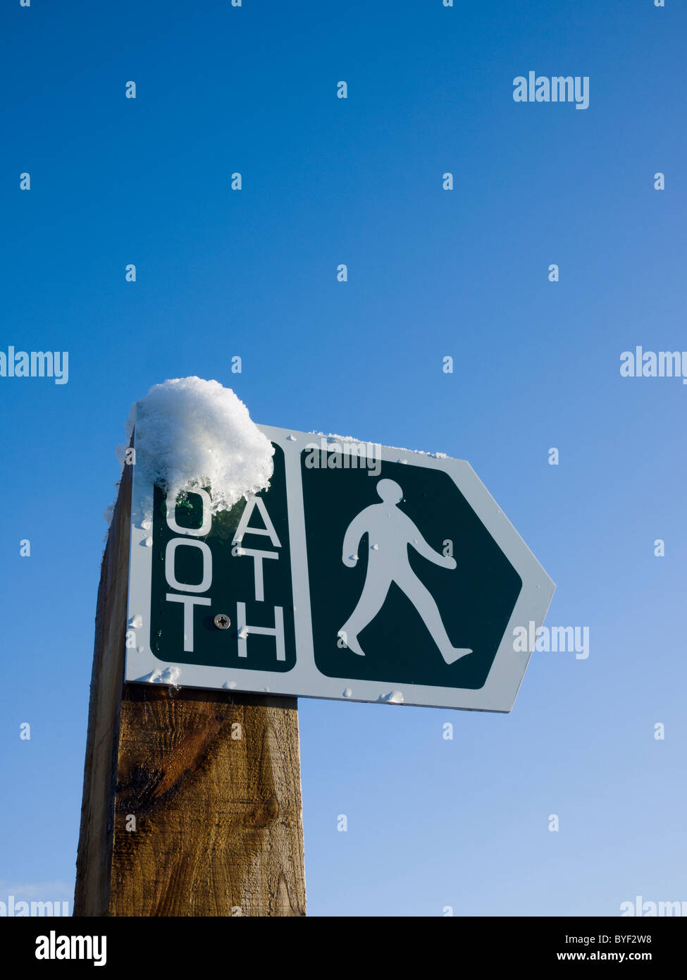 Footpath sign with snow against a blue sky. Wrington, North Somerset, England. Stock Photo