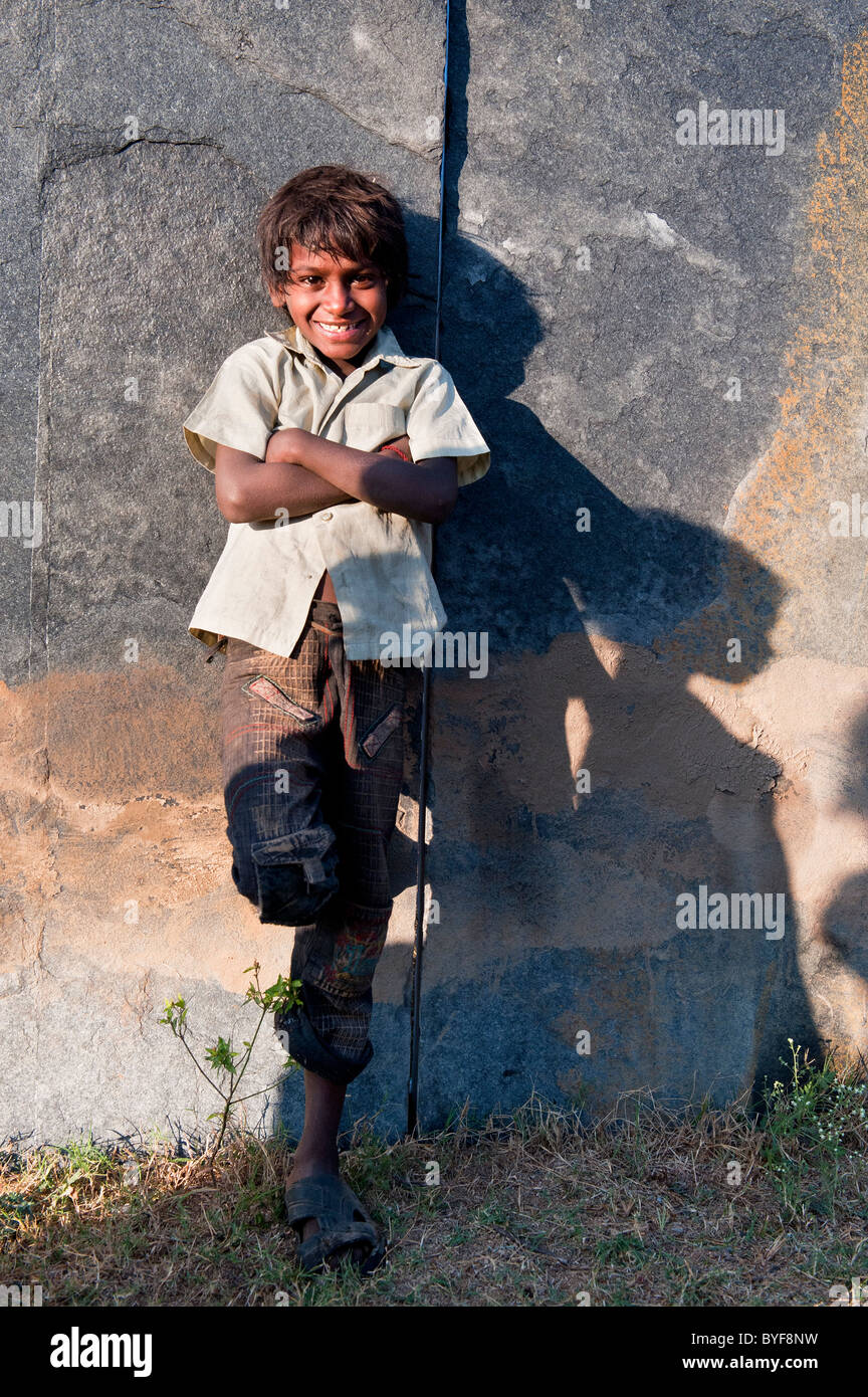 Happy young poor lower caste Indian street boy smiling leaning against