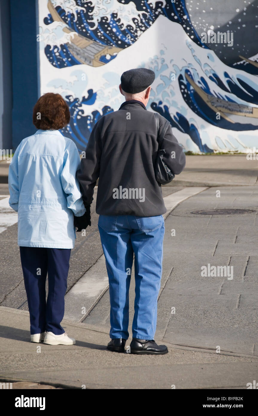 A mature adult couple waits at an intersection before crossing the street in downtown Olympia, Washington. Stock Photo