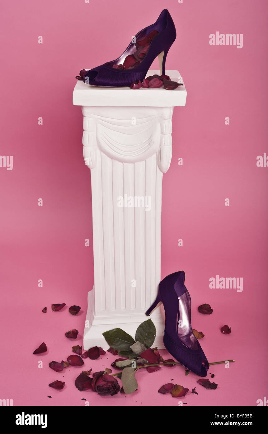 Purple high-heel shoes on pedestal with rose petals and a dying rose Stock  Photo - Alamy