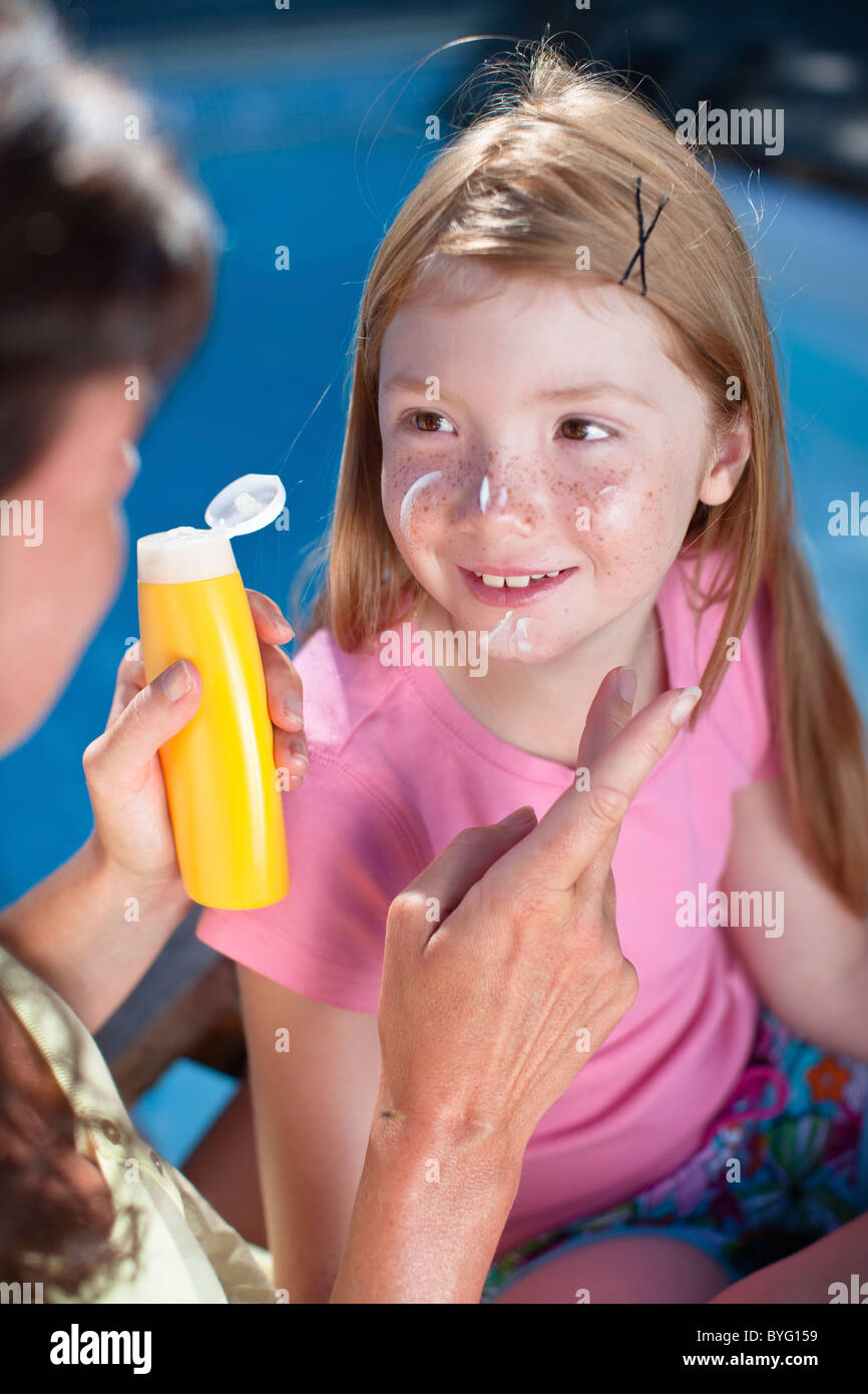Mother applying suntan lotion on her daughters face Stock Photo Alamy