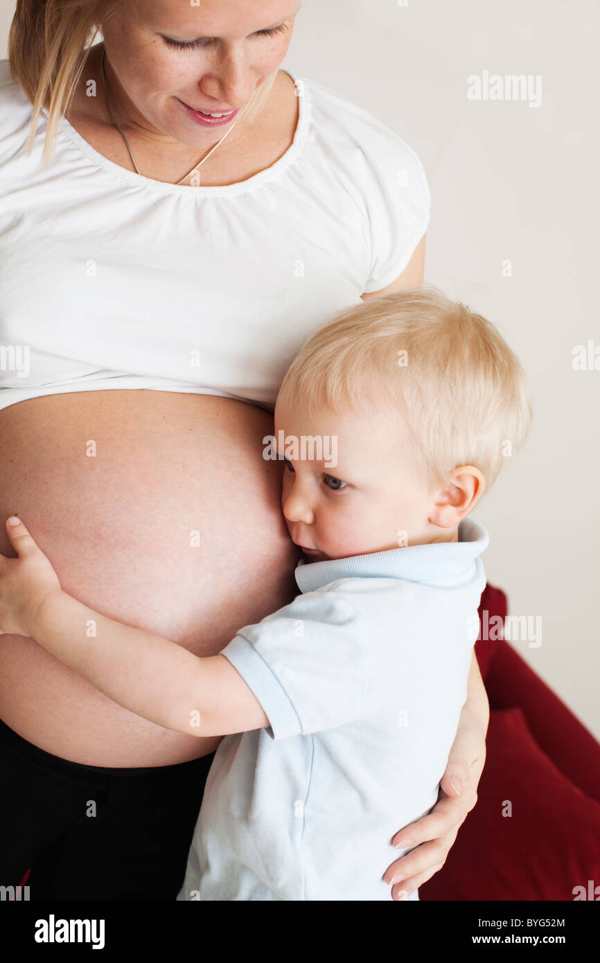 Boy listening to pregnant mothers stomach Stock Photo