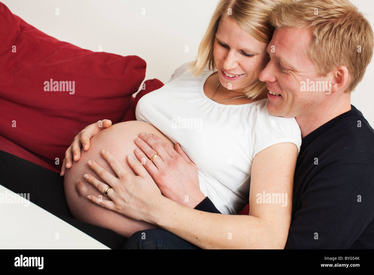 Man embracing pregnant woman on sofa Stock Photo - Alamy