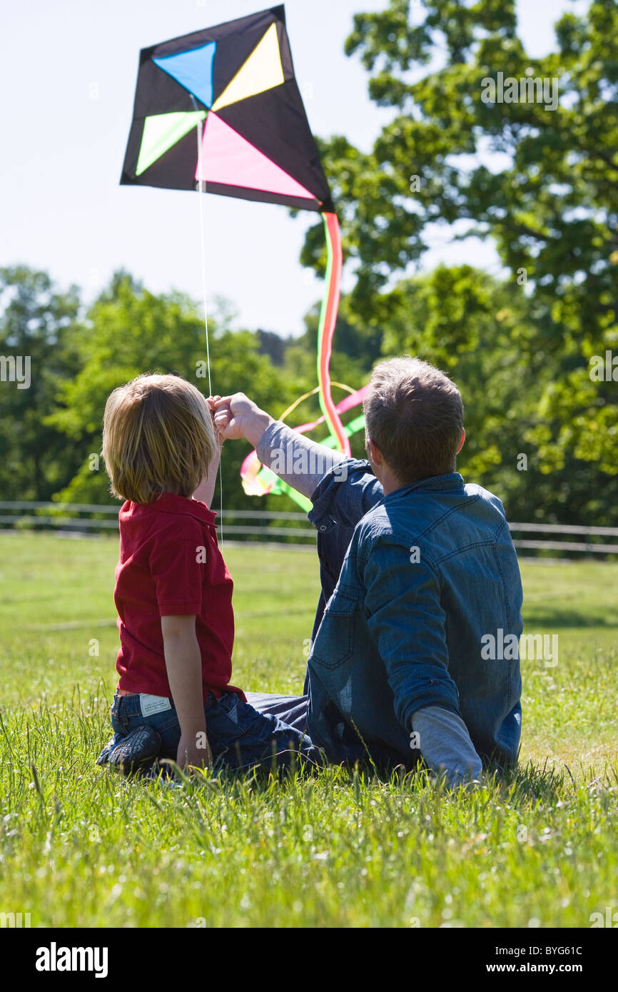 Father and son sitting on grass with kite Stock Photo - Alamy