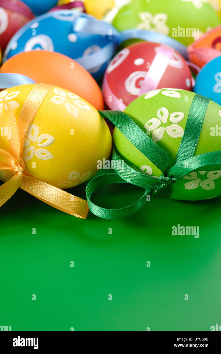 Painted easter eggs with bows over green background Stock Photo - Alamy