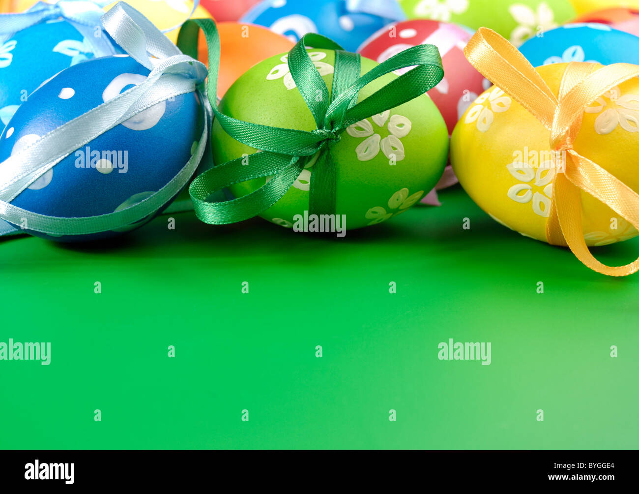 Painted easter eggs with bows over green background Stock Photo - Alamy