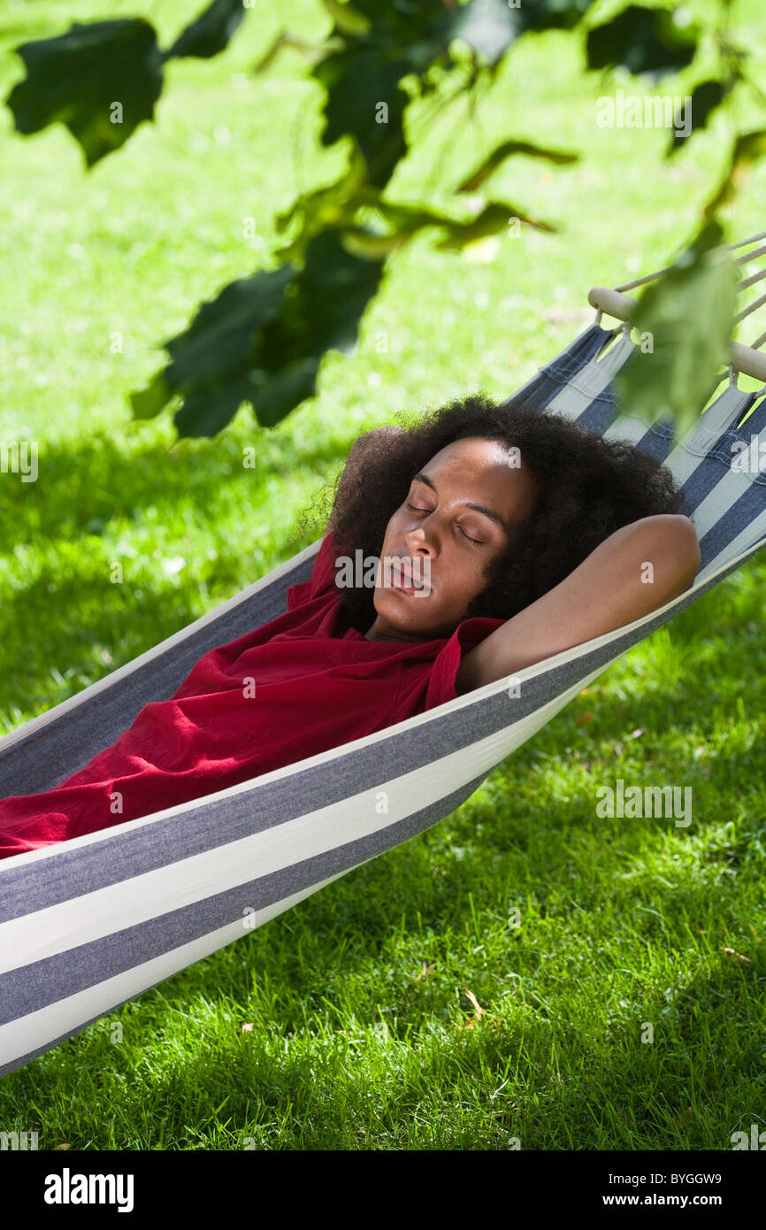 Young man with afro hair sleeping in hammock in park Stock Photo