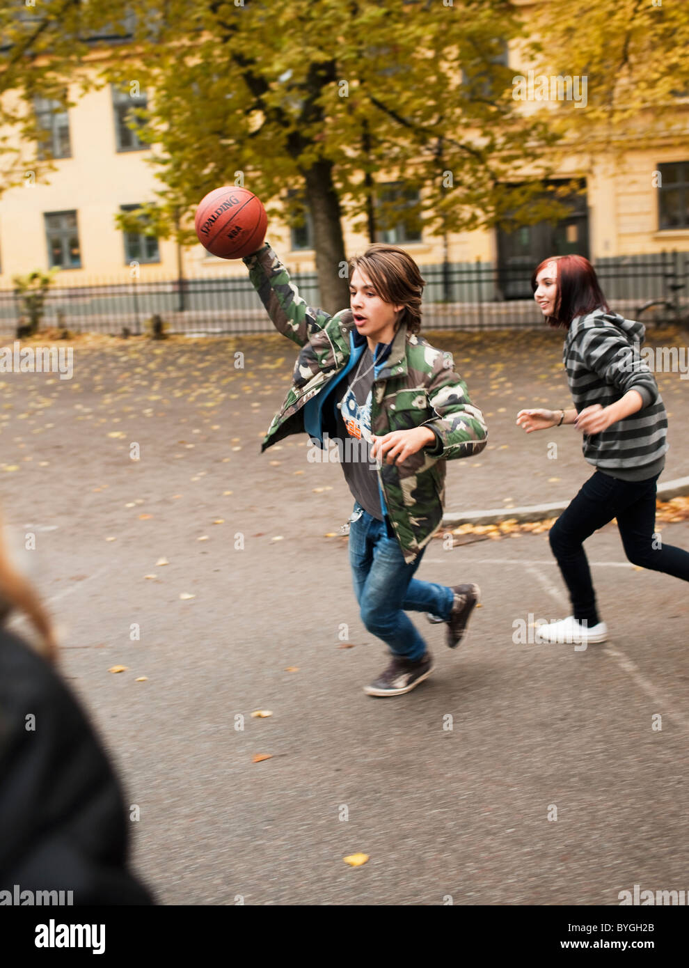 Teenage girls playing basketball in schoolyard Stock Photo