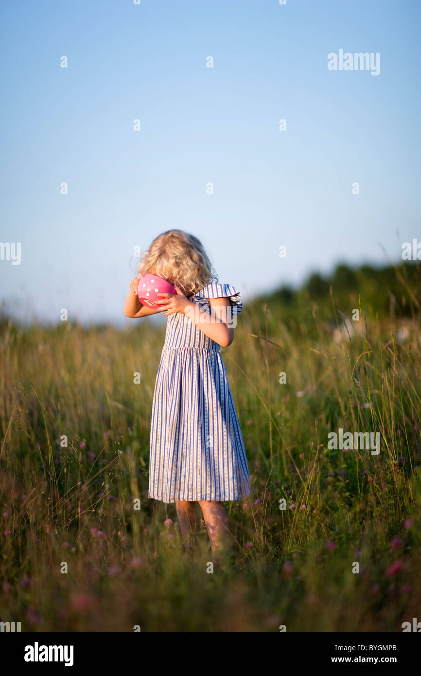 Girl standing on meadow drinking from bowl Stock Photo