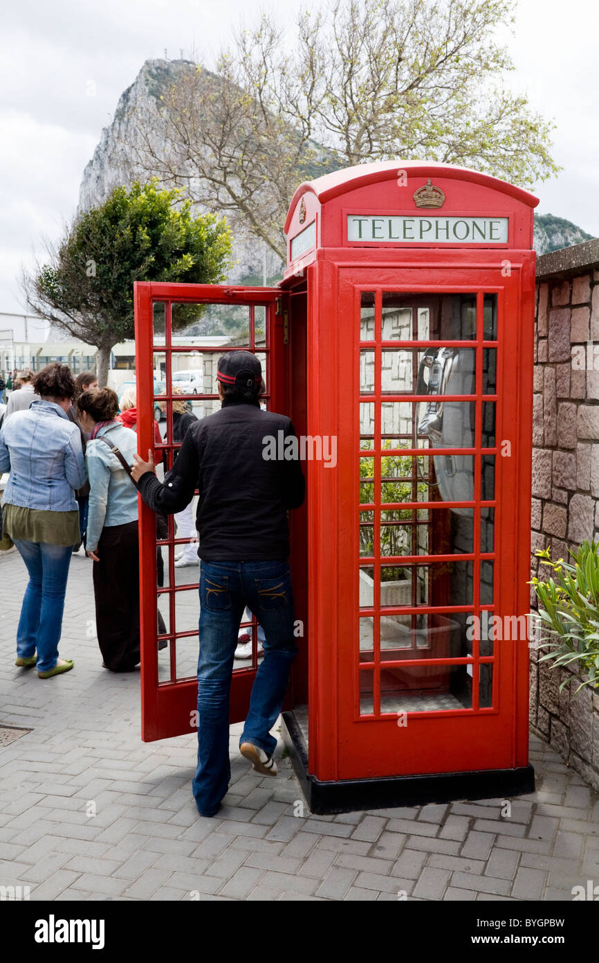 Young man / tourist entering an original K6 red telephone / phone call box on Gibraltar, near border with Spain. Rock of Gibraltar. Stock Photo
