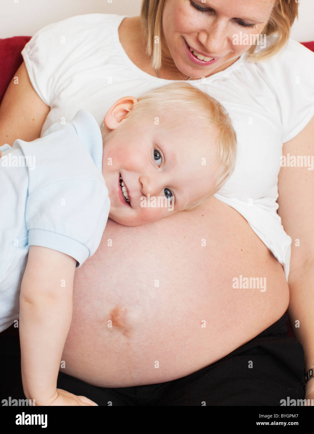 Boy listening to pregnant mothers stomach Stock Photo