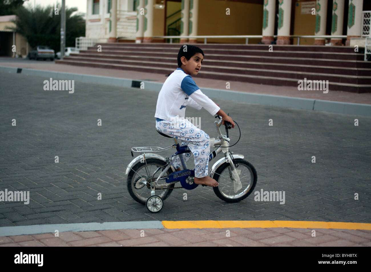 Boy on a bicycle with stabilisers in the UAE Stock Photo