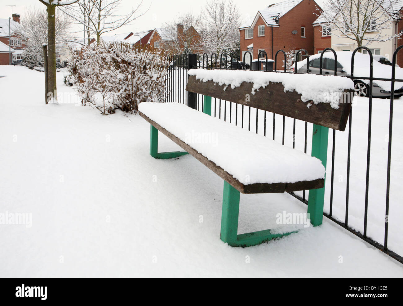 Snow on green park bench Stock Photo