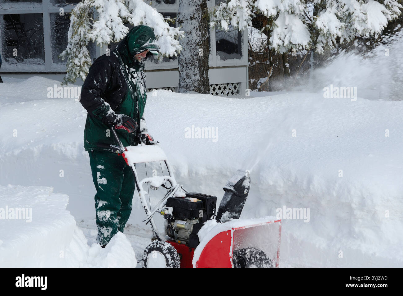 Man using a modern snow blower to clear a driveway the morning after a winter blizzard Stock Photo