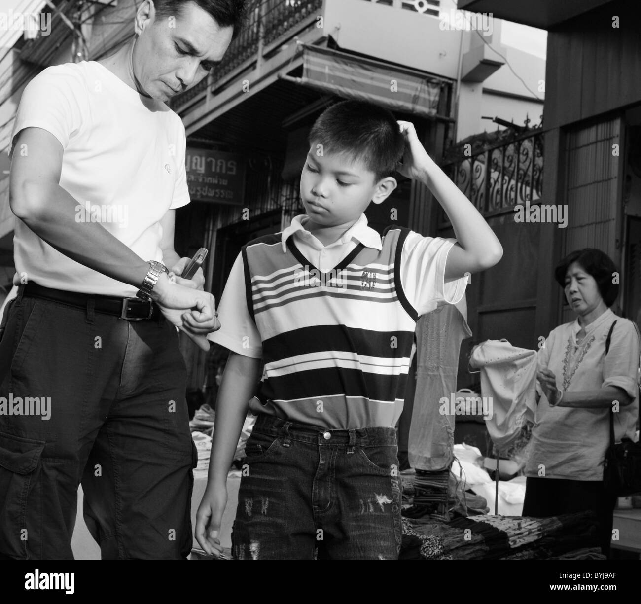 Black and white photograph of a Thai boy and man telling the time Stock Photo