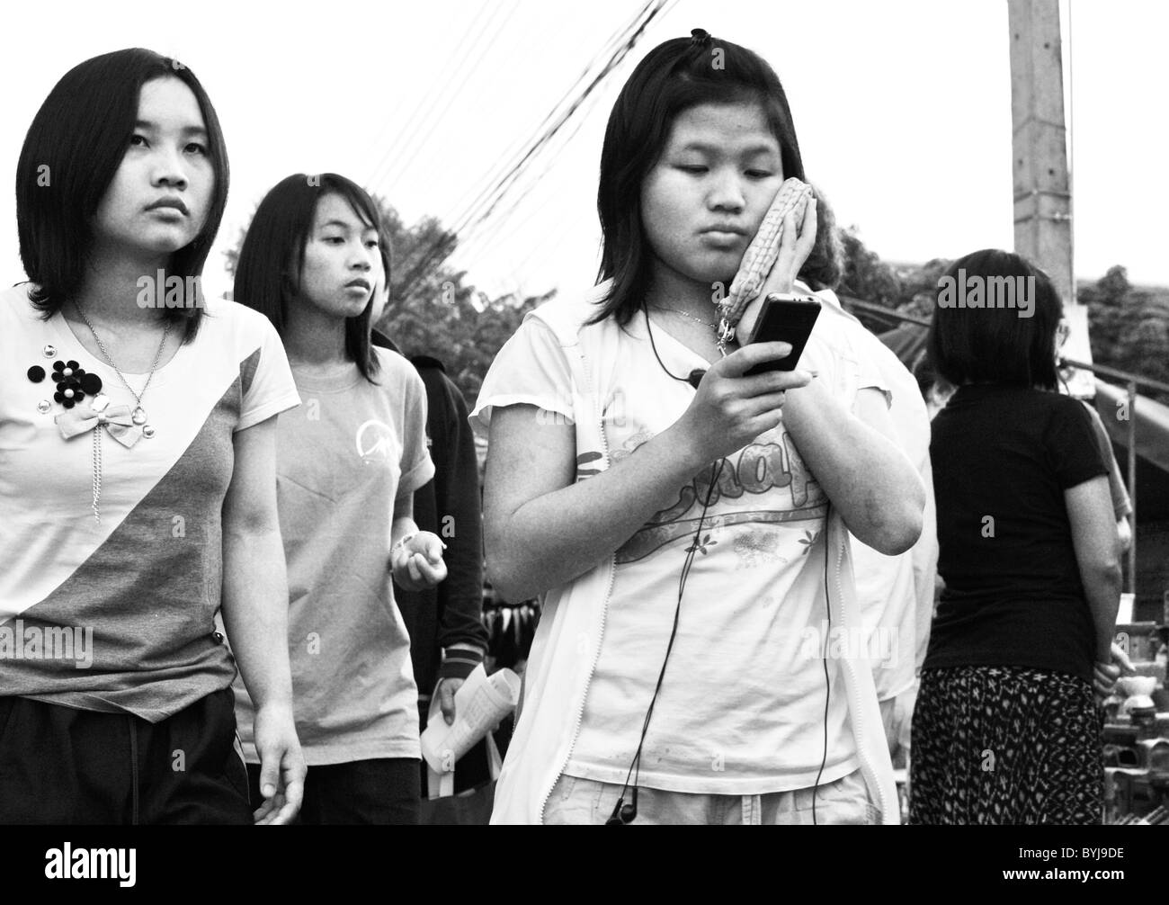 Black and white photograph of three young Thai women walking along a street Stock Photo