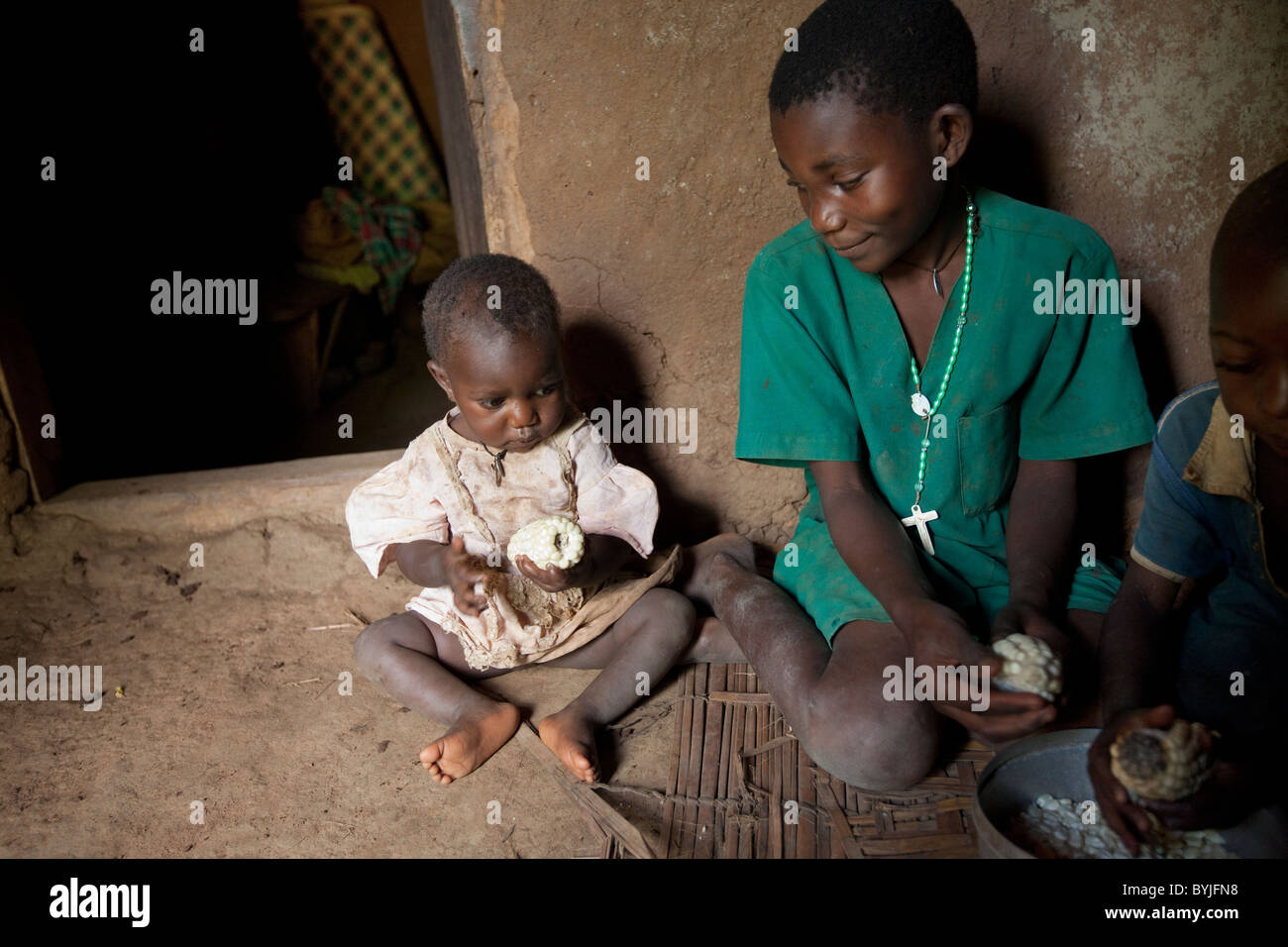 A family shares a meal together in their mud home in Masaka, Uganda, East Africa. Stock Photo