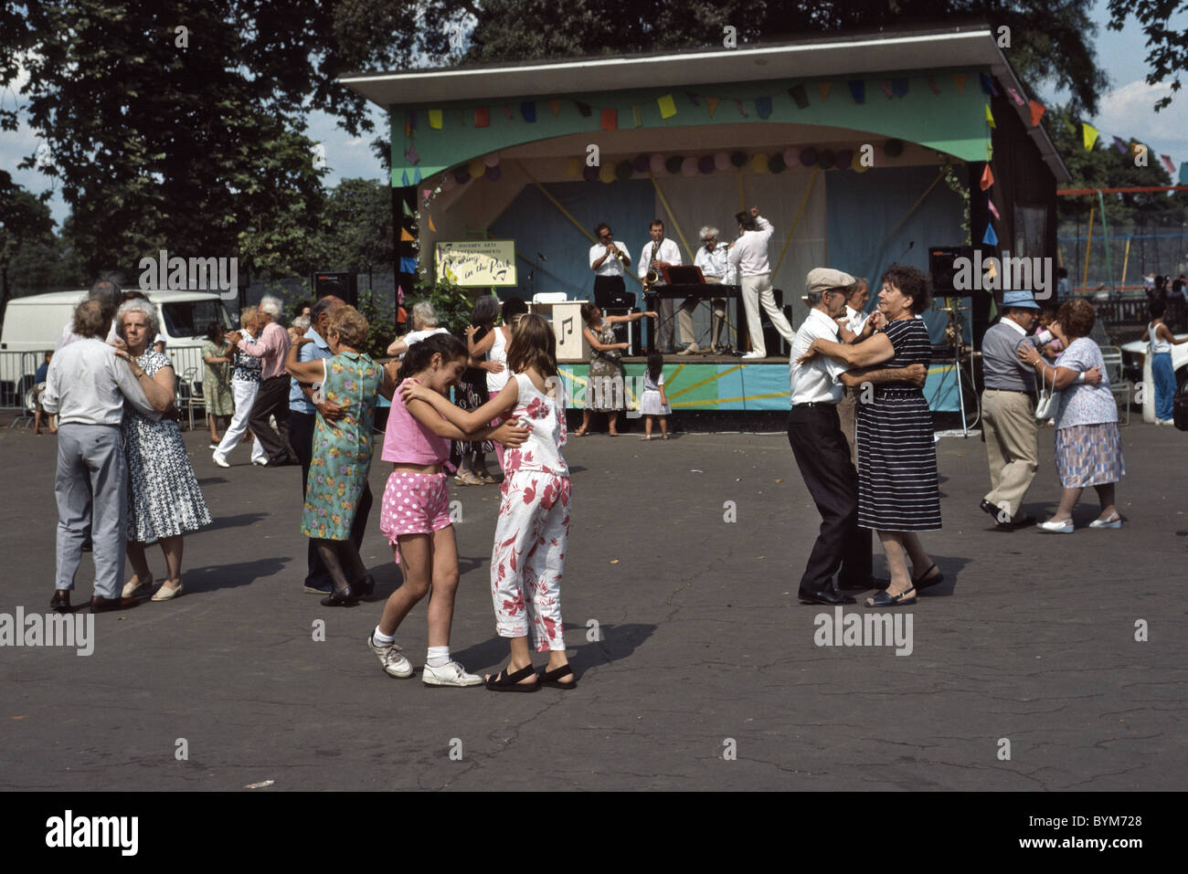 Outdoor Tea Dance in the park with old couples and young girls dancing Stock Photo